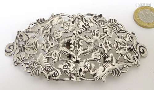 A silver plate buckle decorated with various mythical bird and beast and human mask decoration.