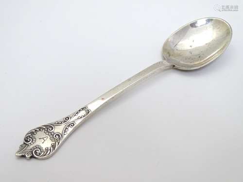 A silver Christening spoon with scroll decoration.