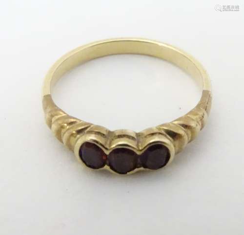 A vintage yellow metal ring set with three garnets.