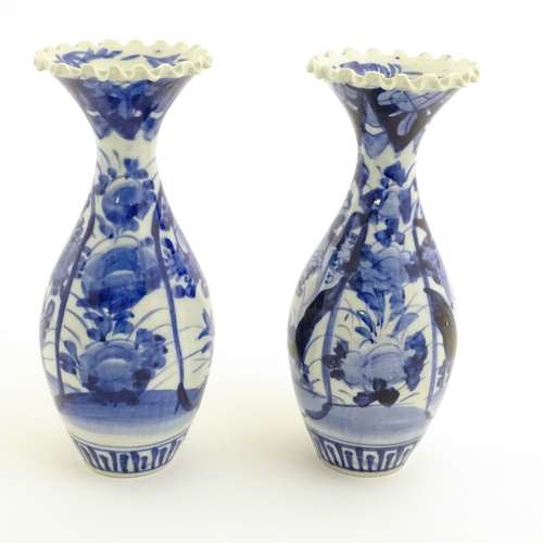 A pair of blue and white Japanese vases with ribbon rims decorated with flowers. Approx.