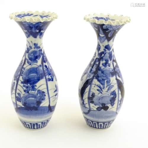 A pair of blue and white Japanese vases with ribbon rims decorated with flowers. Approx.
