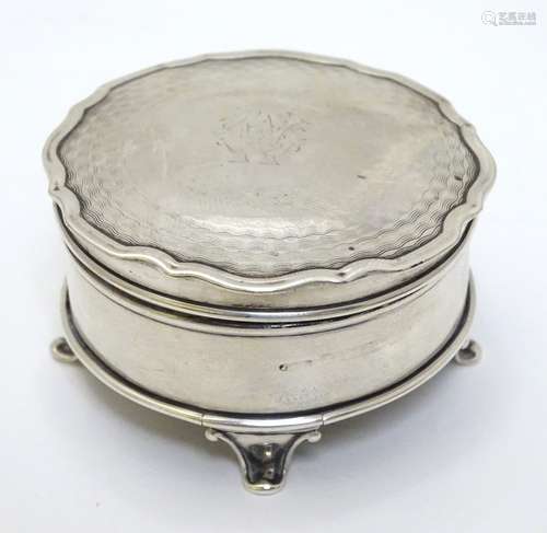 A silver ring box of circular form with engine turned decoration to hinged lid and standing on four