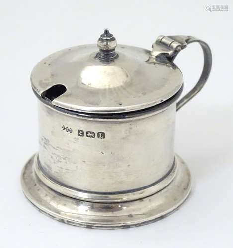 A silver mustard pot with blue glass liner.