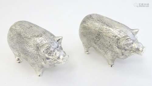 A pair of white metal novelty pepperettes formed as pigs.