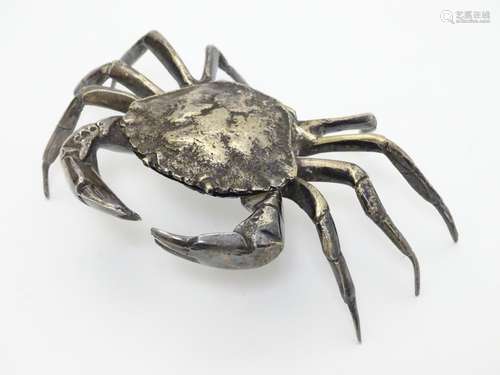 A white metal model of a crab, the body forming a small box with shell section hinging open.