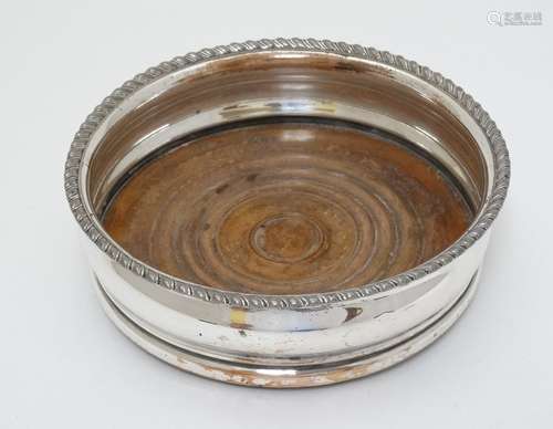 A silver plate coaster with turned wooden base.