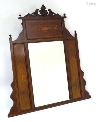 A late 19thC / early 20thC mahogany mirror with carved floral pediment flanked by urn finials.