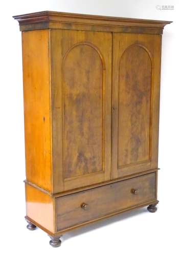 A mid / late 19thC mahogany wardrobe with moulded cornice above two large doors with arched panels,