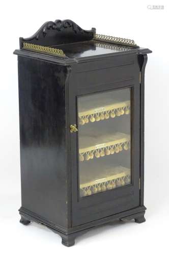 A late 19thC / early 20thC ebonised music cabinet with cupids bow carved wooden gallery and pierced