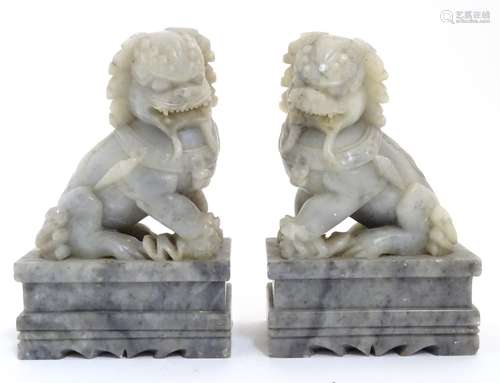 A pair of Chinese grey jadeite like temple dogs on squared socles. (handed).