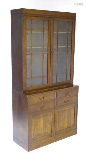 An early 20thC oak glazed bookcase with astragal glazed doors opening to reveal shelves within,