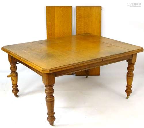 An early 20thC oak extending dining table with rectangular moulded top,