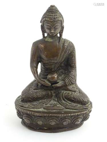 A cast bronze Buddha sat cross legged on a lotus flower base.