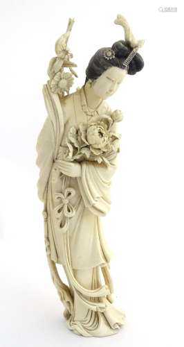 A Japanese Meiji carved large ivory figure of a woman holding a peony. Signed under.