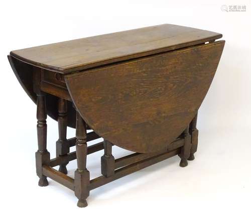 A late 18thC oak gateleg table opening to show its oval form, with single short drawer to one end,