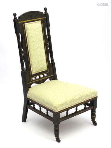 An ebonised Aesthetic Movement nursing chair with floral carving to the cresting rail,