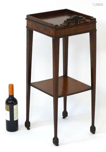 An early 19thC mahogany two tier urn stand with carved decoration to the face and upstand,