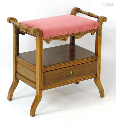 An early 20thC walnut adjustable piano stool with turned handles,