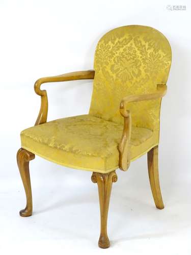 An Art Deco walnut open armchair with arched back, swept arms with shaped arm supports,