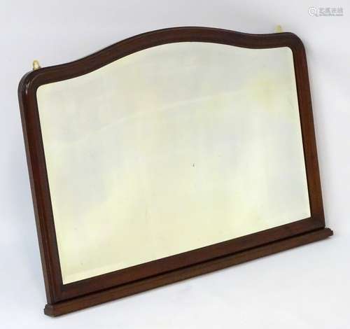 A 20thC mahogany mantle mirror with bevelled edge, shaped top and a stepped base.