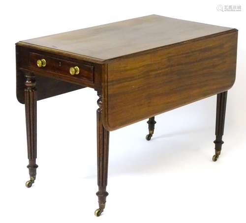 An early 20thC mahogany pembroke table flanked by drop flaps,