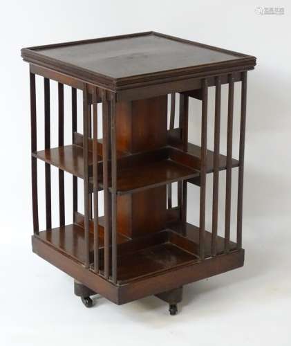 An early 20thC mahogany revolving bookcase with a moulded square top,
