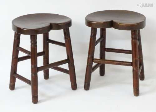 A pair of early 20thC mahogany stools with heart shaped saddle seats,