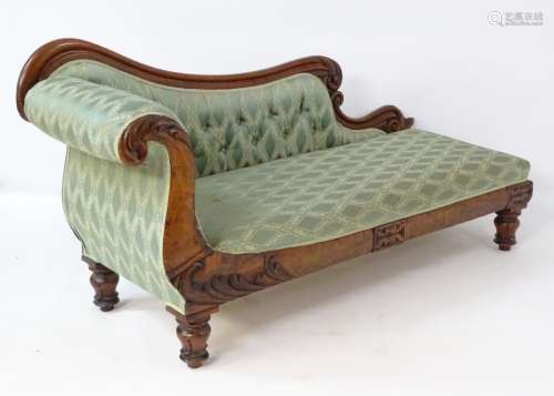 A Victorian chaise lounge having a shaped show wood back with scrolling detail,