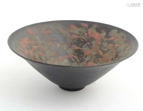 An Oriental ceramic conical shaped bowl with red and grey on black decoration.