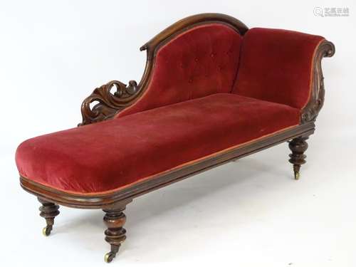 A Victorian mahogany chaise lounge with floral carved frame and deep buttoned upholstered back,