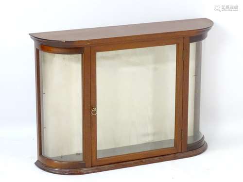 A glazed mahogany wall hanging cabinet with shaped front and single internal glass shelf.