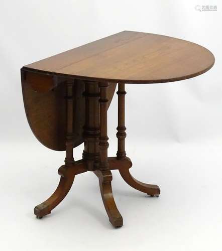 An early 20thC walnut Sutherland table with central column surrounded by four turned supports,