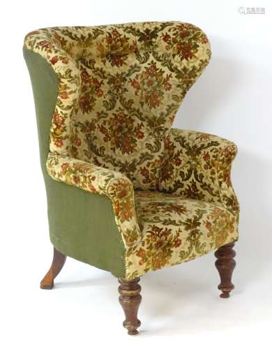 A late 19thC / early 20thC barrel back wing armchair with floral upholstery and shaped arms,