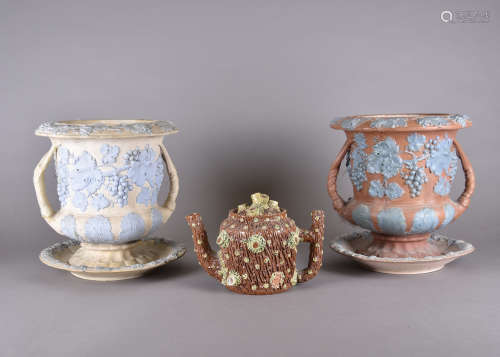 A pair of stoneware twin-handled urns, applied grape and vine decoration on stands, 27 cm high,