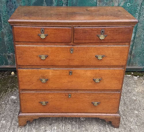 An antique oak chest-of-drawers, two short over three graduated long drawers, bracket feet, in two