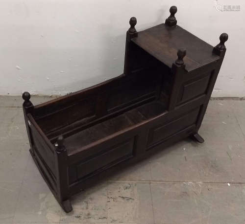 A 17th Century oak cradle, rectangular body and hood on two curved rockers, six finials, 93 cm