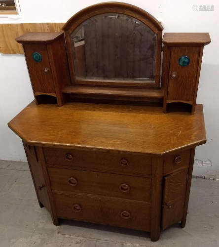 An early 20th Century Arts and Crafts oak dressing table, arched bevelled framed mirror flanked by