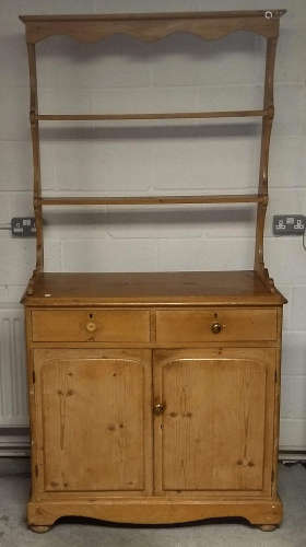 A 19th Century waxed pine dresser, plate rack with shaped pediment above two short drawers, two