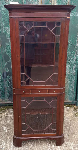 A 20th mahogany corner display cabinet, two astral glazed doors divided by three drawers, shaped