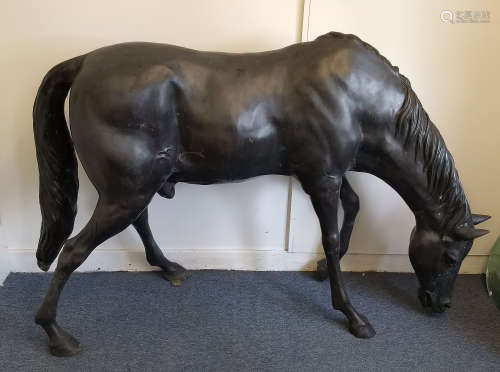 A contemporary bronzed garden sculpture of a horse lowering it's head to feed, 135 cm high x 194