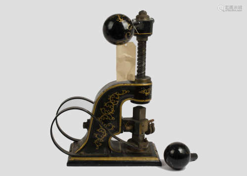 A late 19th/early 20th Century painted metal stamping machine, gilt scroll decoration on black