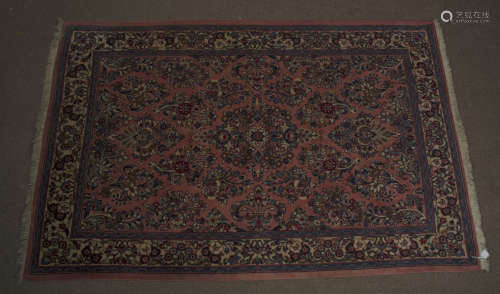 A Middle-Eastern woollen rug, floral and scroll decoration on terracotta ground,