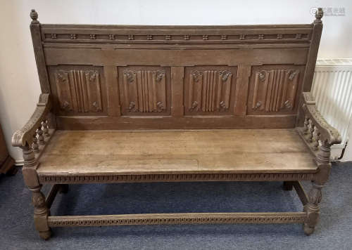 An early 20th Century oak settle, four linenfold panels to back, turned naturalistic supports united