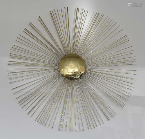A contemporary wall mounted gilt metal sculpture of a sunburst after a design by Jonathan Adler,
