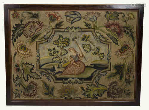 A woolwork tapestry with central cartouche depicting a shepherdess in a landscape, surrounded by
