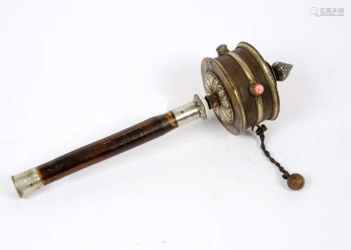 A Tibetan prayer wheel, wooden handle, leather covered wheel decorated with metalwork and inlaid
