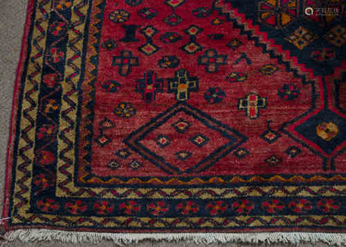 A Kazak woollen rug, central indigo pole medallion on red ground, indigo and ivory border,