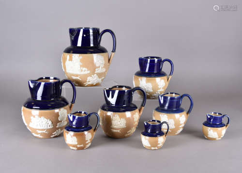 A set of eight Doulton Lambeth graduated stoneware jugs, applied scenes of hunting, smoking,