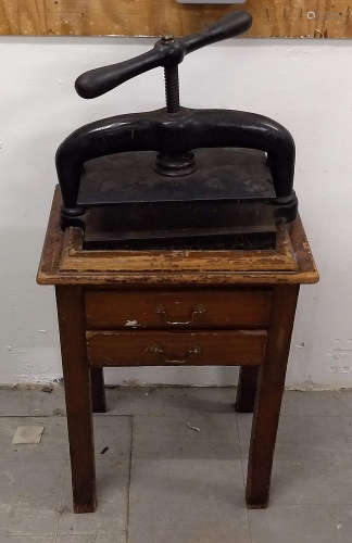 A 19th Century cast iron book press raised on mahogany stand, two frieze drawers, 56 cm wide x 38 cm