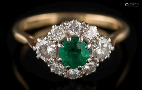 An emerald and diamond cluster ring: the central round emerald approximately 4.5mm diameter x 3.